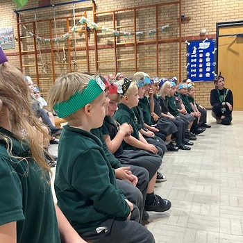 Plant yn esitedd mewn rhes yn y neuadd